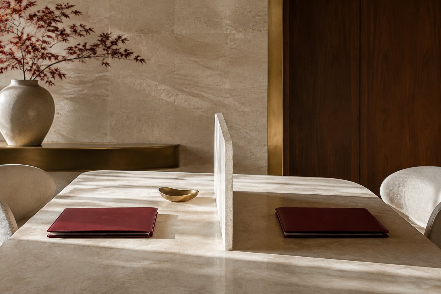 Two burgundy folders on opposite sides of a limestone meeting table with a central ivory divider.