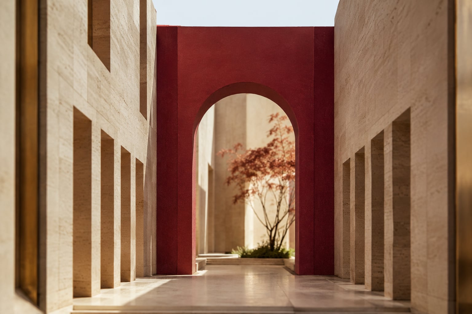 Two converging limestone corridors meeting beneath a burgundy architectural arch.