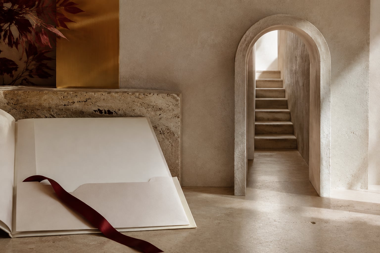 An ivory document folder with a burgundy ribbon beside an abstract limestone passageway.